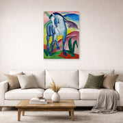 Unframed poster print of Franz Marc's Blue Horse displayed on a wall in a living room