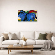 Unframed poster print of Franz Marc's The Little Blue Horses displayed on a wall in a living room