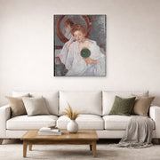 Unframed poster print of Mary Cassatt's Denise at Her Dressing Table displayed on a wall in a living room