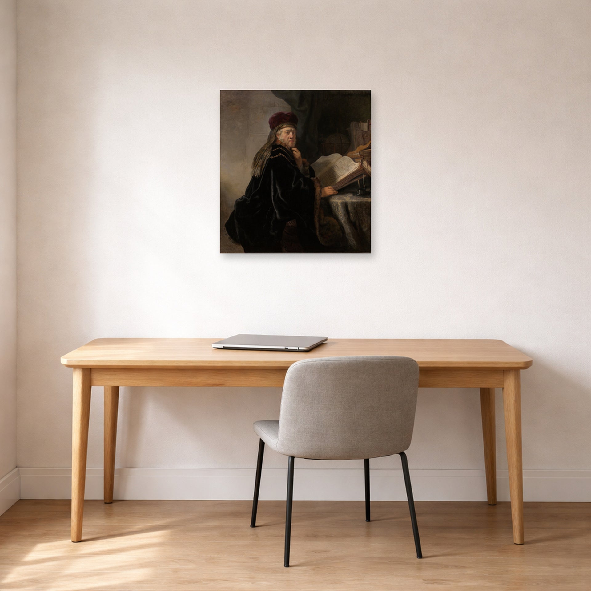 Unframed poster print of Rembrandt's A Scholar Seated at a Desk displayed on a wall in an office