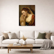 Unframed poster print of Rembrandt's A Weeping Woman displayed on a wall in a living room