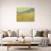 Unframed poster print of Vincent van Gogh's Wheatfield with a Reaper displayed on a wall in a living room